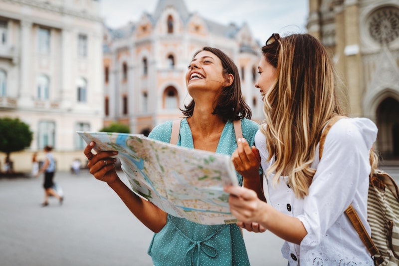 Deux étudiantes en tourisme lisant une carte en voyage, rentrée décalée de janvier à Atlas Institute